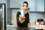 Woman demonstrating bottle of olive oil while cooking