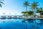 Beach and sea with umbrella and chair around swimming pool